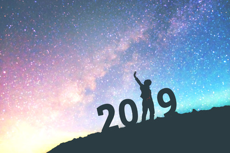 Silhouette young man Happy for 2019 new year background on  the Milky Way galaxy pointing on a bright star. dark sky tone . Vintage grain tone.の写真素材