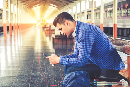 Travel man using mobile phone at train stationの写真素材