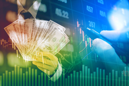 Businessman Holding money US dollar bills on digital stock market financial exchange information and Trading graph backgroundの写真素材