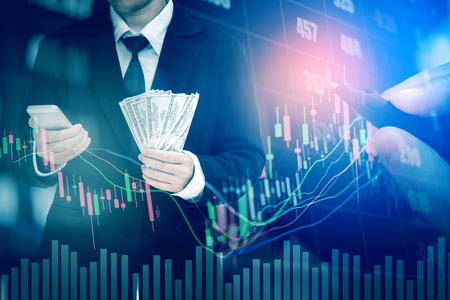 Businessman Holding money US dollar bills on digital stock market financial exchange information and Trading graph backgroundの写真素材