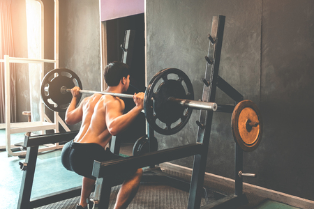 Muscular Man built athlete working out in gym and weightlifting machine and lifting barbellの写真素材