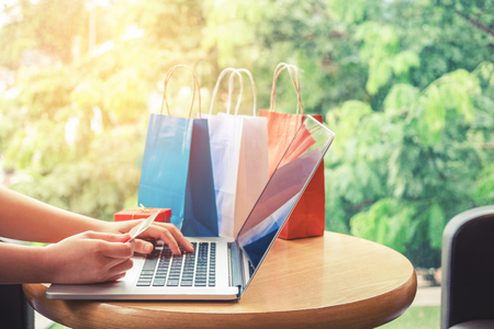 Woman shopping online using laptop with credit card enjoyingの写真素材