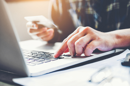 Man's hands typing laptop keyboard and holding credit card online shopping conceptの写真素材