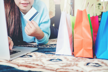 Woman shopping online using laptop blank screen with credit card enjoying in homeの写真素材