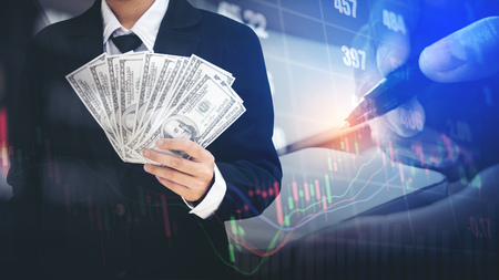 Businessman Holding money US dollar bills on digital stock market financial exchange information and Trading graph backgroundの写真素材