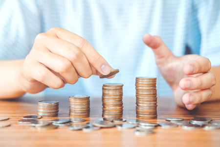 Saving money concept man hand putting coin stack finance for budgetの写真素材