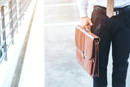 Businessman holding a briefcase travellers walking outdoorsの写真素材
