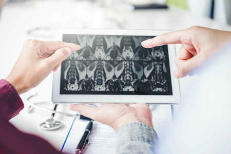 Doctor consulting with patient presenting results  x-ray film on digital tablet About the problem of the patientの写真素材