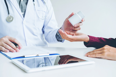 Doctor or physician recommend pills medical prescription to male Patientの写真素材