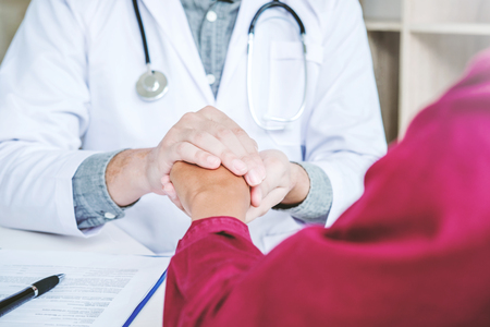 Doctor holding hands for comforting and care patientの写真素材
