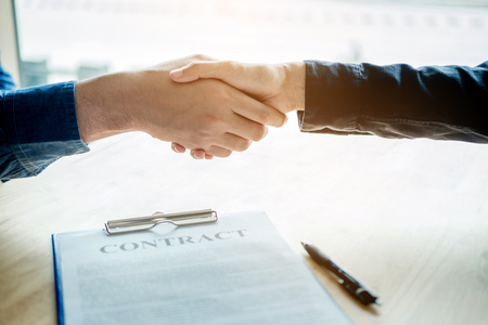 Business people negotiating a contract handshake between two colleaguesの写真素材