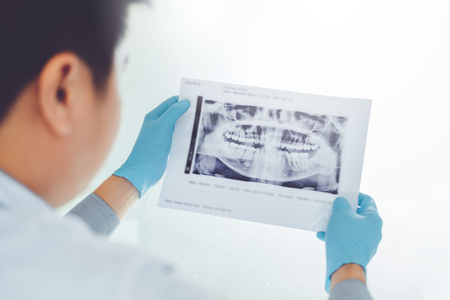 Dentist consulting with patient presenting results on Dental x-ray film About the problem of the patientの写真素材