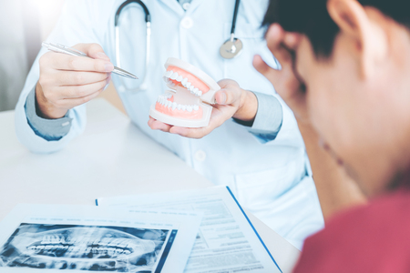 Dentist consulting with patient presenting results on Dental x-ray film About the problem of the patientの写真素材