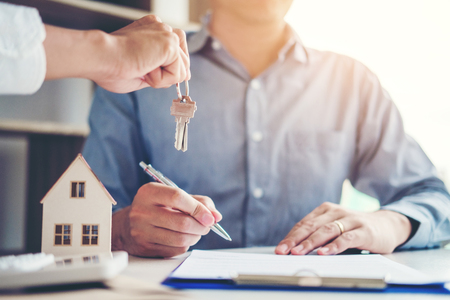 Sale agent giving house keys to customer and sign agreement contract, Insurance Home conceptの写真素材