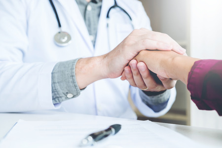 Doctor holding hands for comforting and care patientの写真素材
