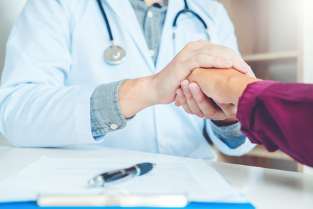Doctor holding hands for comforting and care patientの写真素材
