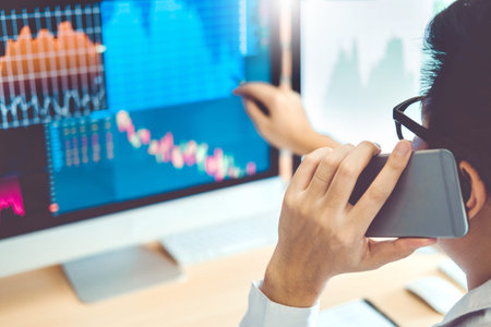Businessmen trading stocks online  Using Mobile phone Investment discussing and analysis graph stock...