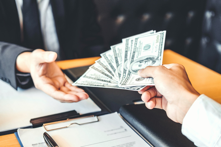 Corruption concept,Business manager passing money dollar bills corruption bribery to another businessmanの写真素材