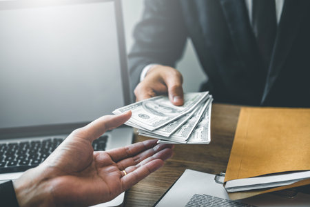 Corruption concept,Business man passing money dollar bills corruption bribery to businessman manager