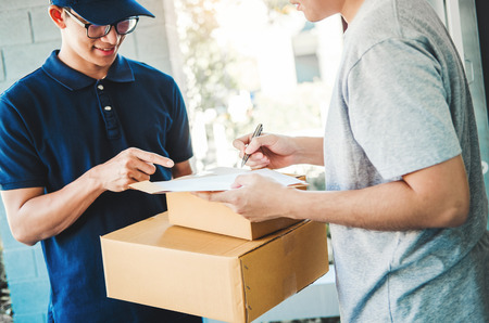 Customer Man signature in clipboard to receive package from professional delivery man at homeの写真素材