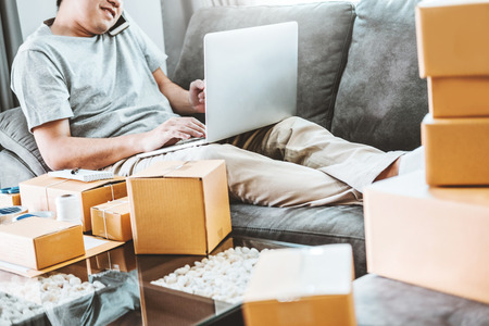 Young man startup entrepreneur small business owner Talking his Phone with customers at home,Online business seller packaging and delivery conceptの写真素材