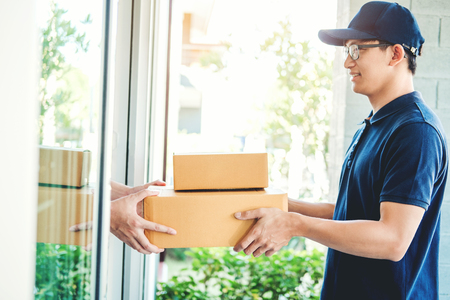 Asian Man hand accepting a delivery boxes from professional deliveryman at homeの写真素材