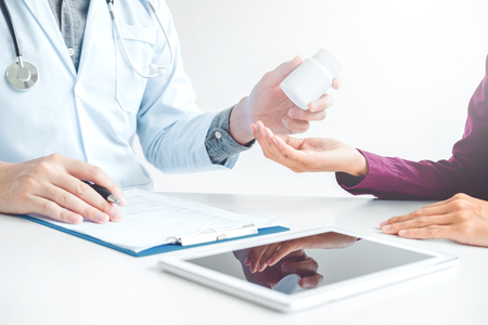 Doctor or physician recommend pills medical prescription to male Patientの写真素材
