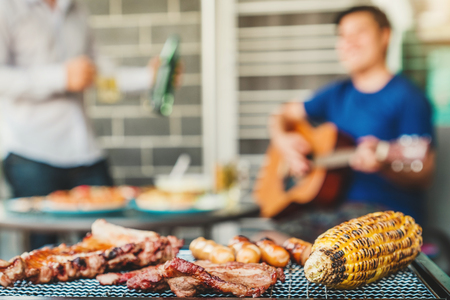 Afternoon Party Group friends enjoying drinking beer with barbecue and roast pork happy playing guitar enjoying home partyの写真素材
