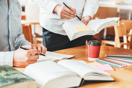 High school or college students studying and reading together in libraryの写真素材