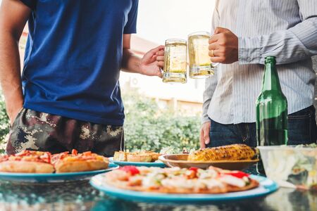 Afternoon Party Group friends enjoying drinking beer with barbecue and roast pork happy while enjoying home partyの写真素材