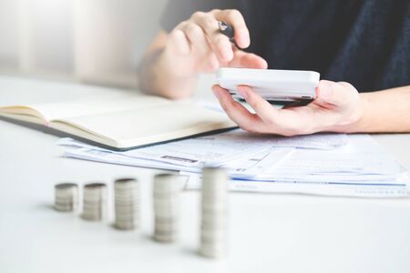 Man using calculator Accounting Calculating Cost Economic bills with money stack step growing growth saving money in home , finance conceptの写真素材