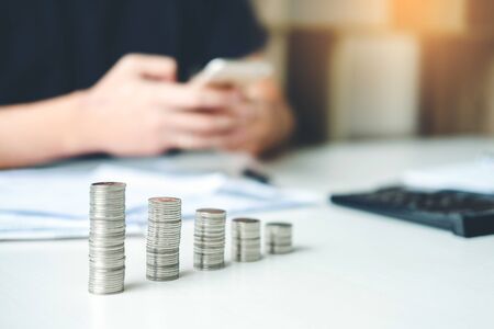 Man using calculator Accounting Calculating Cost Economic bills with money stack step growing growth saving money in home , finance conceptの写真素材
