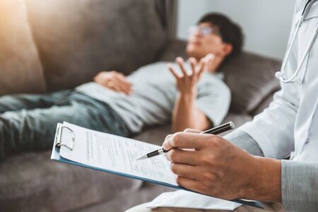 Doctor consulting and diagnostic examining with men's patient health disease and writing on prescription record information document visit patient's homeの写真素材