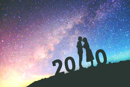 2020 Newyear Silhouette young couple Happy for romantic background on the Milky Way galaxy pointing on a bright star.の写真素材