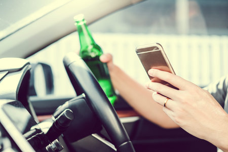 Drunk man driving a car on the road holding bottle beer Dangerous drunk driving concept