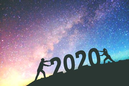 2020 Newyear  Couple tries to push number of 2020 Happy new year background on  the Milky Way galaxyの写真素材