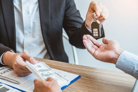 Sale agent giving Car key to customer and sign agreement contract, Insurance car concept.の写真素材