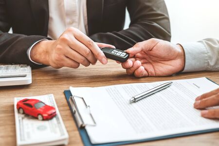 Sale agent giving Car key to customer and sign agreement contract, Insurance car concept.の写真素材
