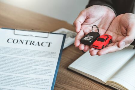 Sale agent giving Car key to customer and sign agreement contract, Insurance car concept.の写真素材