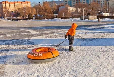 MOSCOW, RUSSIA - JANUARY 06, 2015: Kid pulling a large tube in Muzeon Art Park in Moscow, Russia. Tubing is very popular winter recreational activityのeditorial素材
