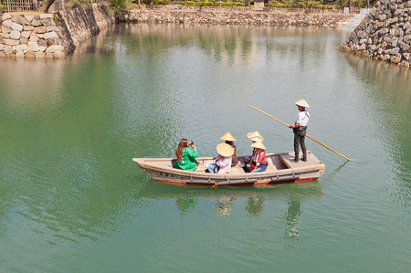 TAKAMATSU, JAPAN - MAY 22, 2015: Tourists in straw hats at a row on traditional boat in the moat of Takamatsu castle, Shikoku Island, Japanのeditorial素材