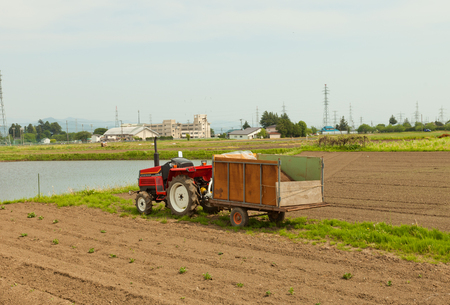 MARIOKA, JAPAN - MAY 22, 2017: Small red Japanese tractor (Yanmar F18d type) with cart on the field near Morioka city, Japanのeditorial素材