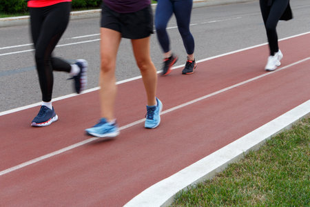 Four girls are running on a jogging road in a park.の写真素材