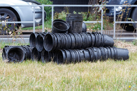 Black plastic pots on the grass near the fence.
