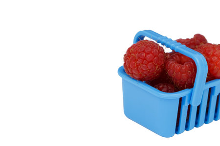 Red raspberries berries in a shopping basket, vegetarian food shopping concept. Isolated on a white...