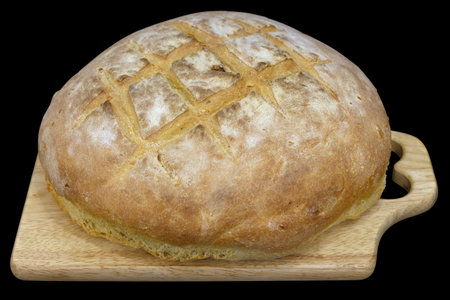 Large round homemade bread on a board, isolated on black.