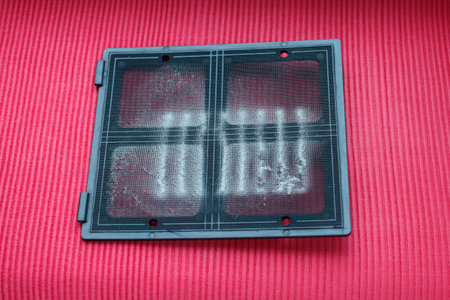 Filled dust filter grill for computer on red cloth.の写真素材