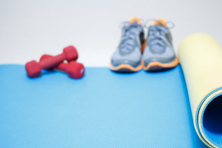 Blurred image of gymnastic rug, sneakers and dumbbell, copy space.の写真素材