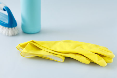 Clean yellow latex gloves and cleaning supplies in the background. copyspace.の写真素材