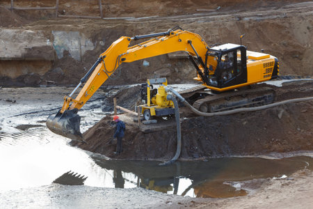 Workers with special equipment are cleaning the pond, pumping out water.